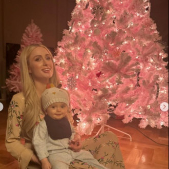 Paris Hilton poses in front of bright pink Christmas tree to celebrate arrival of newborn daughter